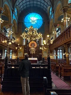 Man standing in ornate, historic synagogue interior.